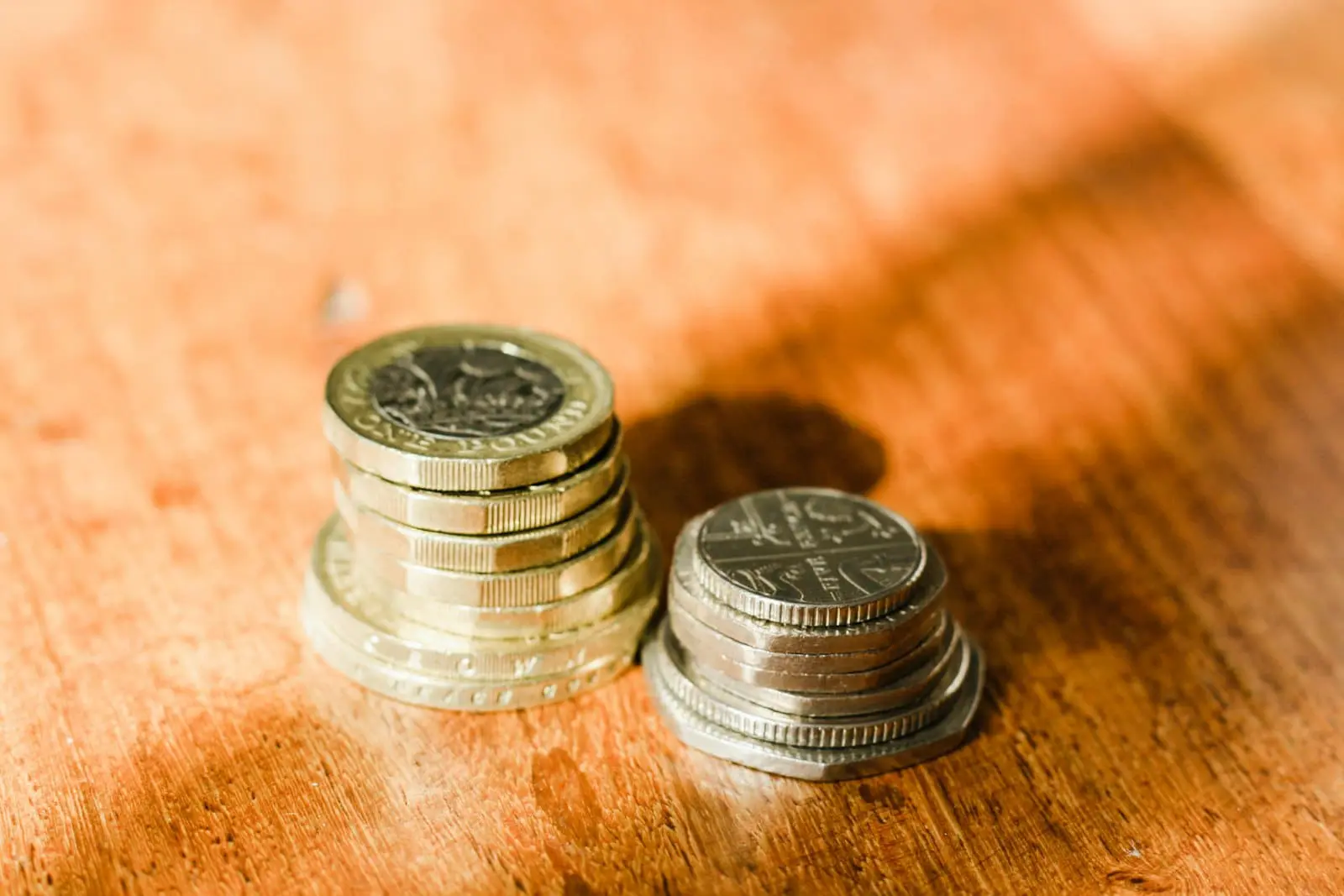 British pound coins arranged on a surface, illustrating saving and investing your first £1,000 in UK markets