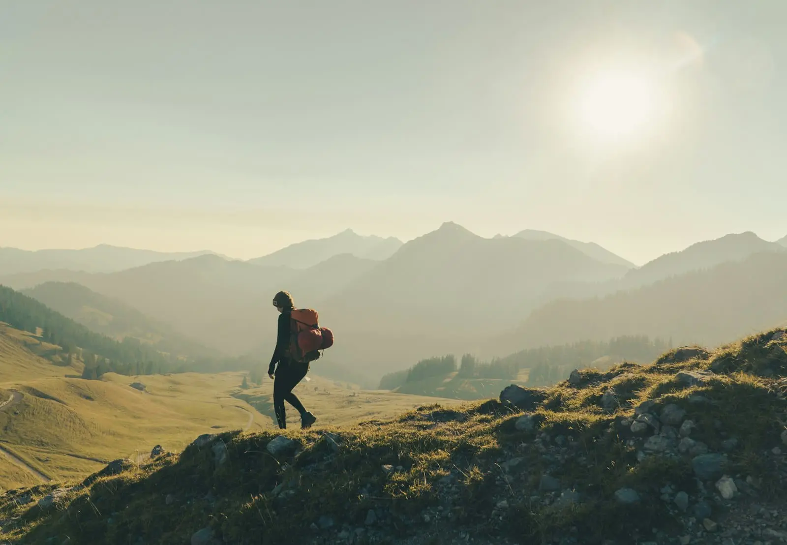 Hiker on a mountain trail in sunny weather, illustrating the freedom and lifestyle choices that financial independence enables