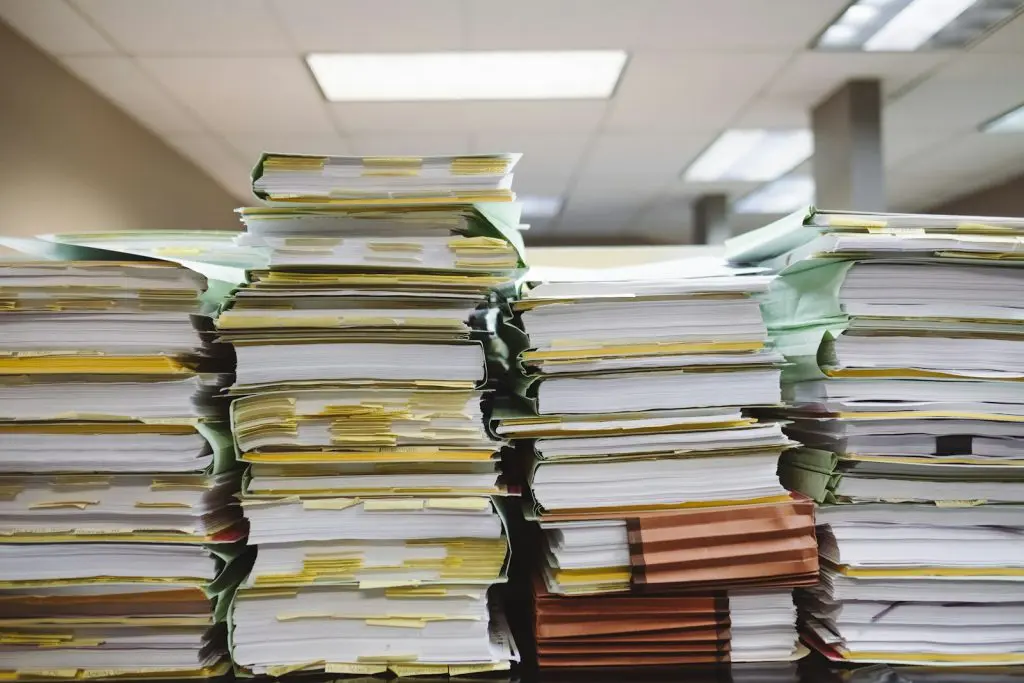 A stack of paper documents and file folders representing estate paperwork and inherited IRA administration