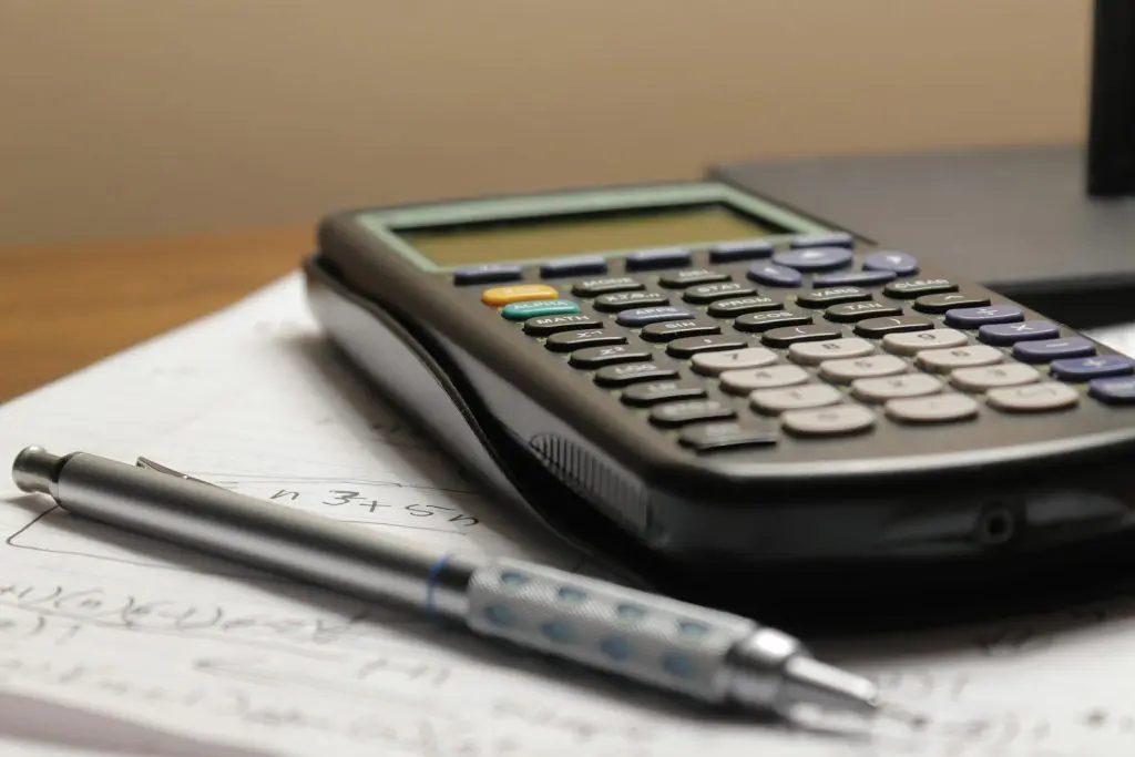 A calculator and pen on paperwork representing the cost and payback of voluntary National Insurance contributions