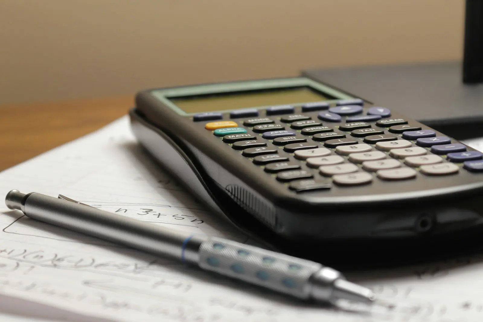 A calculator and pen on paperwork representing the cost and payback of voluntary National Insurance contributions