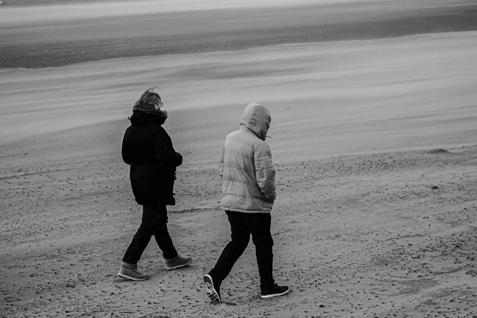 A retired couple walking on the beach representing the decision of when to claim Social Security