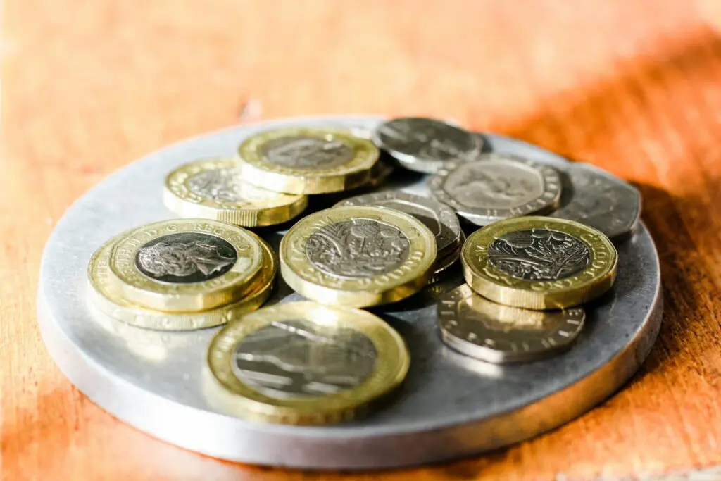 UK pound and two pound coins with twenty pence and five pence pieces scattered on a table